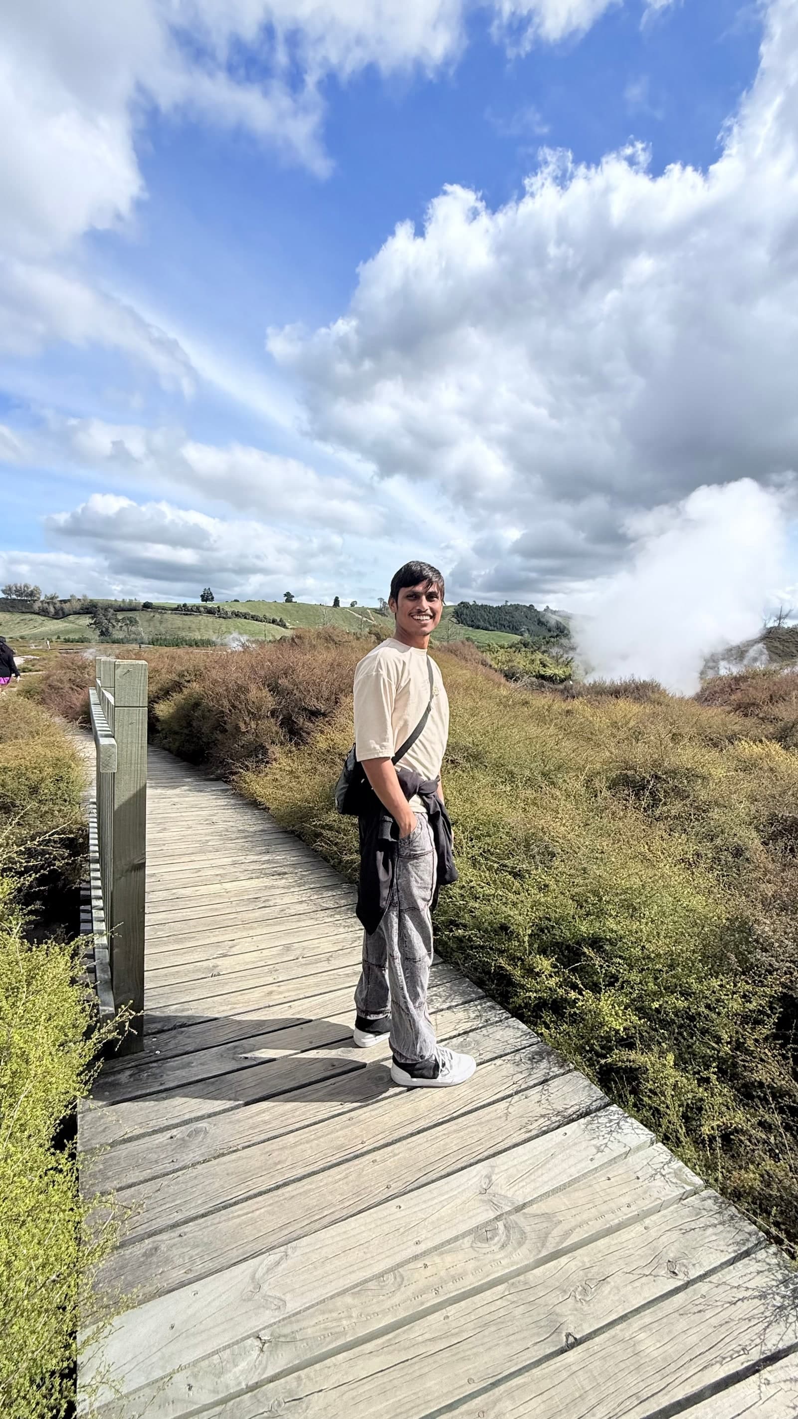 Ashvin Rokade standing on a boardwalk in a New Zealand geothermal landscape